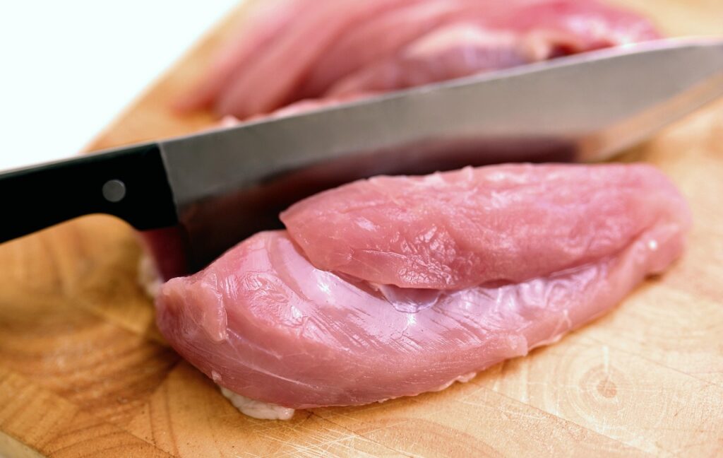 raw meat cut with a knife on a cutting board